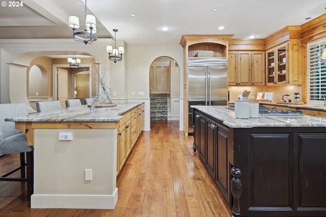 kitchen featuring light stone counters, pendant lighting, a spacious island, and stainless steel built in fridge