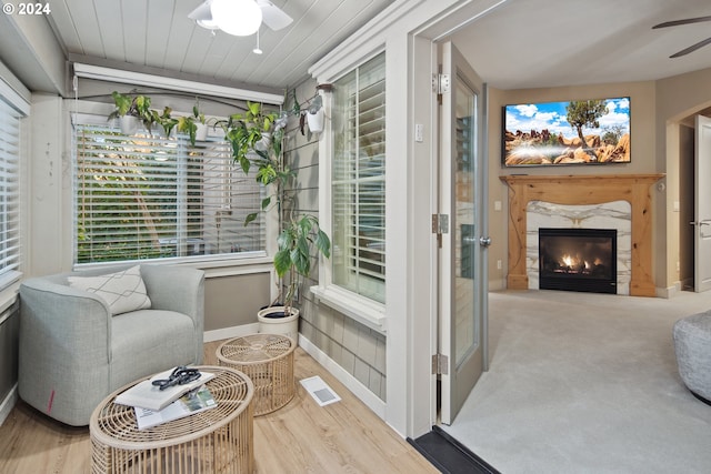 sitting room featuring light hardwood / wood-style floors, a premium fireplace, and ceiling fan