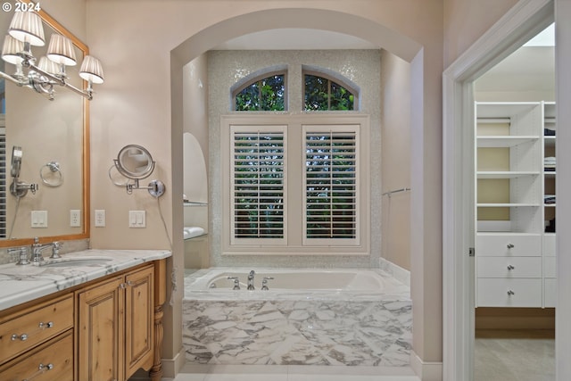 bathroom featuring vanity, tiled bath, and an inviting chandelier