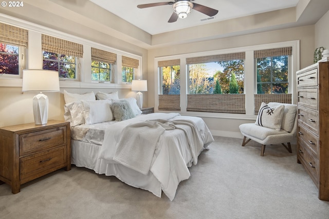 carpeted bedroom with ceiling fan and a tray ceiling