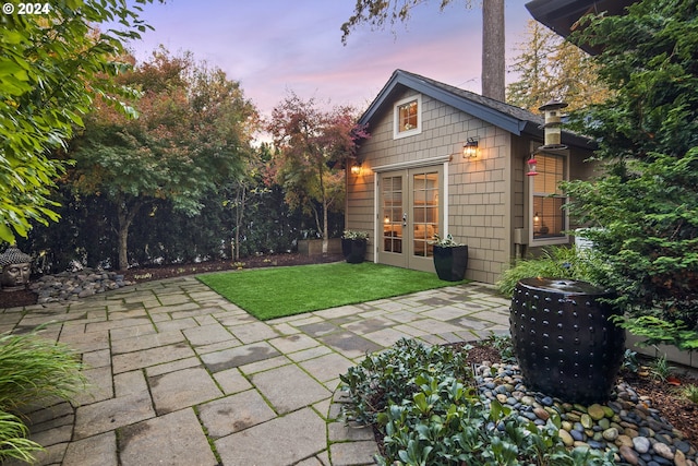 back house at dusk with a yard and a patio