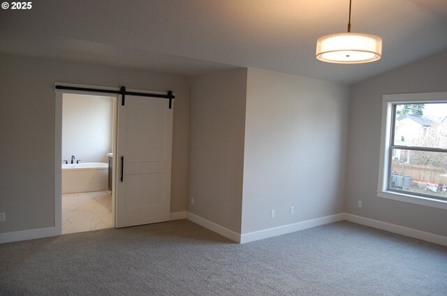 carpeted spare room with a barn door and lofted ceiling