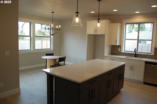 kitchen featuring dishwasher, a center island, white cabinets, sink, and decorative backsplash