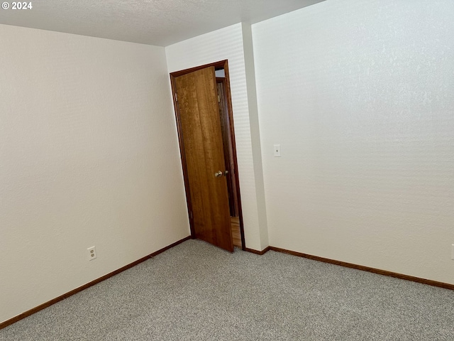 carpeted empty room featuring a textured ceiling