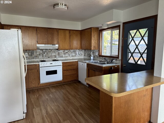 kitchen featuring white appliances, ventilation hood, sink, dark hardwood / wood-style floors, and kitchen peninsula