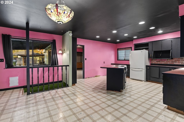 kitchen featuring white fridge, decorative light fixtures, a kitchen island, and light carpet