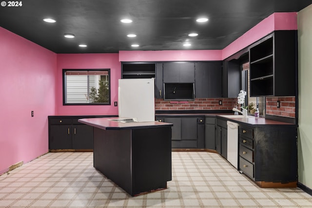 kitchen featuring decorative backsplash, white appliances, a kitchen island, and sink