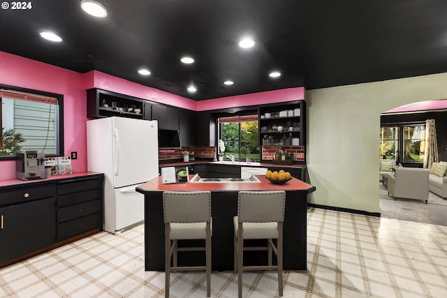 kitchen with a kitchen breakfast bar, stainless steel cooktop, and white fridge