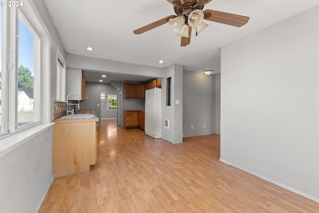 kitchen featuring sink, light hardwood / wood-style floors, white refrigerator with ice dispenser, and a healthy amount of sunlight