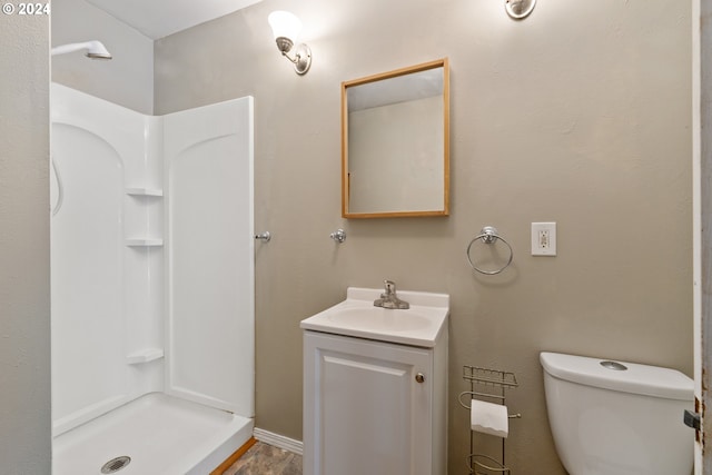 bathroom featuring toilet, vanity, and a shower