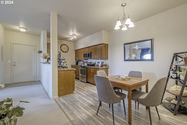 dining area featuring a textured ceiling, light wood-style floors, baseboards, and a chandelier