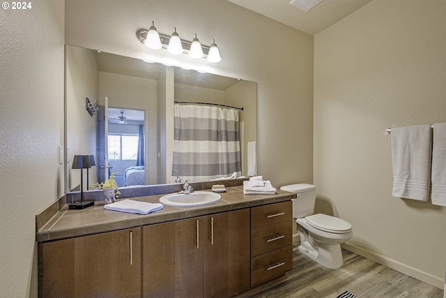 bathroom featuring vanity, toilet, baseboards, visible vents, and wood finished floors