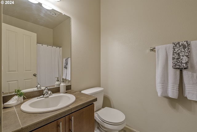 full bath with curtained shower, toilet, and vanity