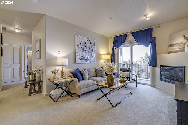 carpeted living area featuring baseboards, a textured ceiling, and a glass covered fireplace