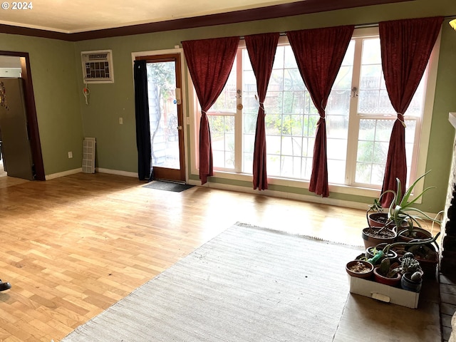 interior space featuring light wood-type flooring, a wall mounted AC, and crown molding