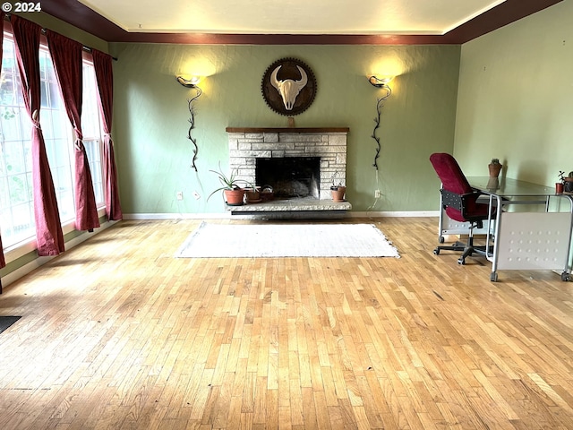 living area featuring a fireplace, baseboards, a healthy amount of sunlight, and hardwood / wood-style flooring