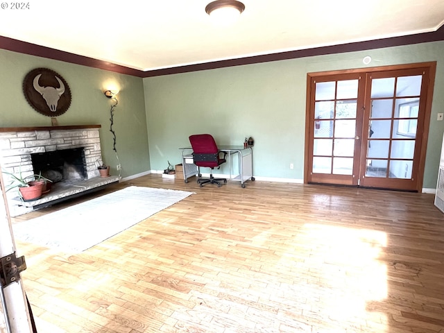 living area with french doors, baseboards, crown molding, wood finished floors, and a fireplace