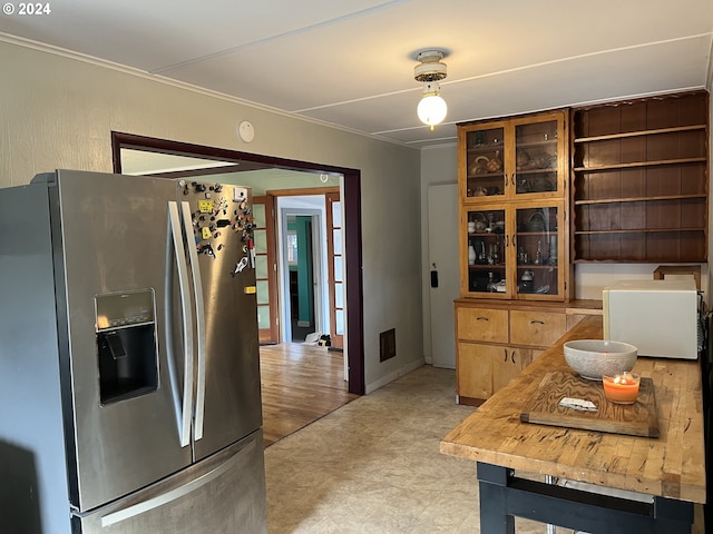 kitchen featuring light floors, ornamental molding, visible vents, stainless steel fridge, and glass insert cabinets