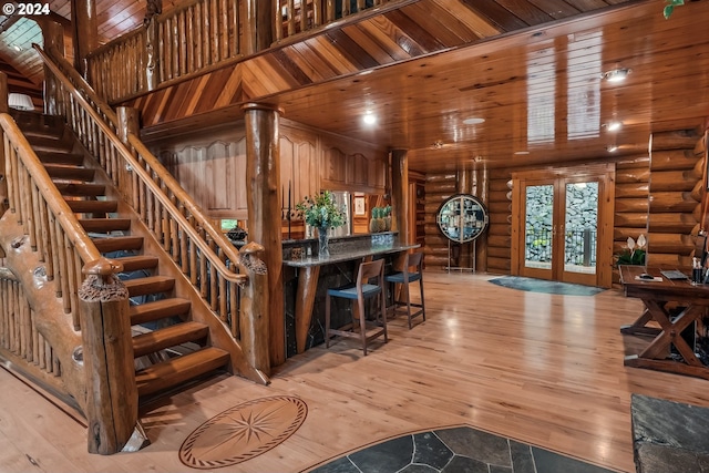 interior space with wooden ceiling, a high ceiling, french doors, light wood-type flooring, and rustic walls