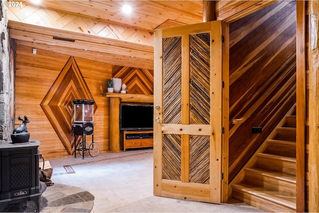 interior space featuring wooden ceiling, wooden walls, and a wood stove