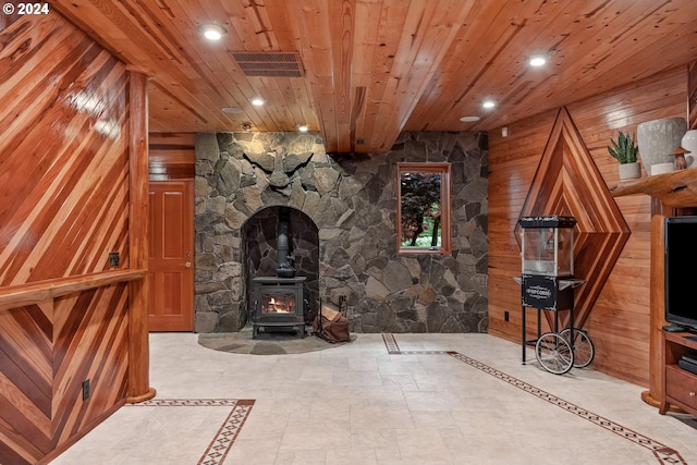 unfurnished living room with a wood stove, wooden walls, and wood ceiling