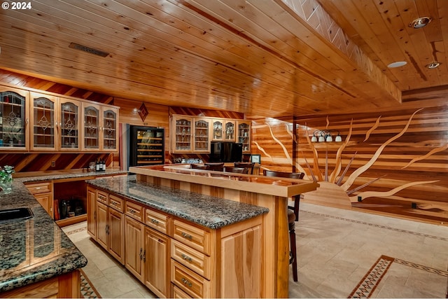 kitchen featuring beverage cooler, wood walls, a kitchen bar, a kitchen island, and wood ceiling