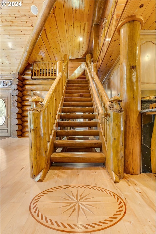 stairway with log walls, hardwood / wood-style floors, and wood ceiling