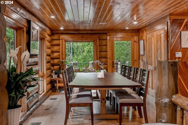 dining space featuring wood walls, wooden ceiling, rustic walls, and light hardwood / wood-style flooring