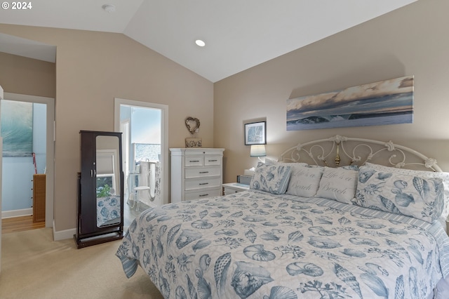 bedroom with lofted ceiling, ensuite bath, and light colored carpet