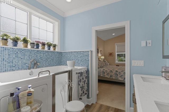 bathroom featuring ornamental molding, vaulted ceiling, hardwood / wood-style floors, and plenty of natural light