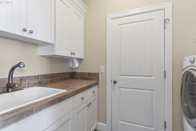 laundry area featuring sink, washer / dryer, and cabinets