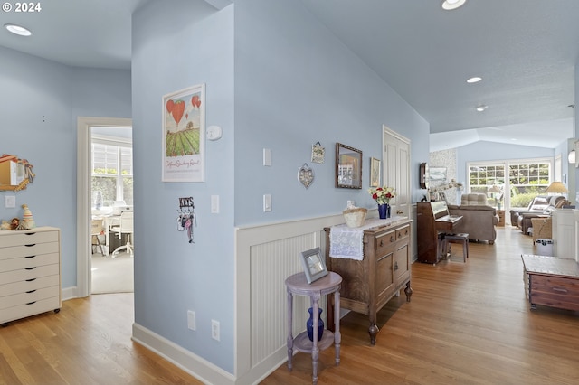 hallway with lofted ceiling and light hardwood / wood-style flooring