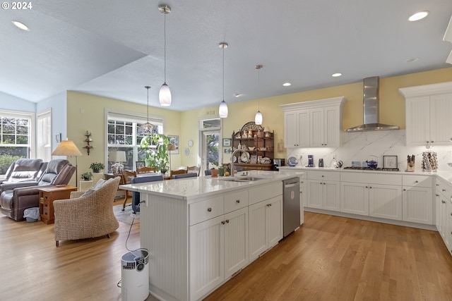 kitchen with wall chimney exhaust hood, white cabinets, a healthy amount of sunlight, and sink