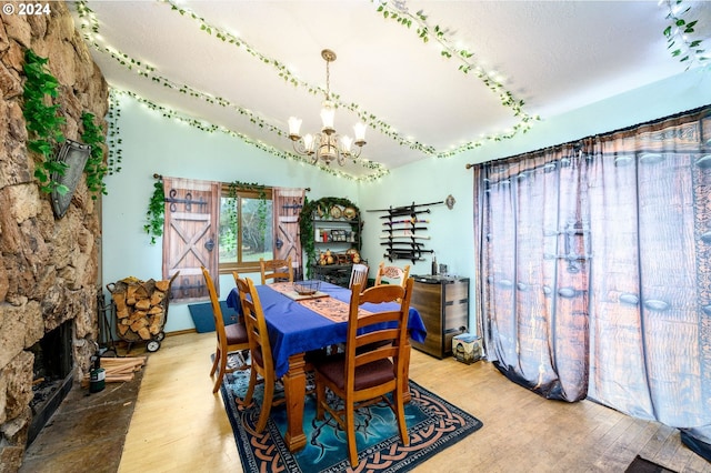 dining room featuring hardwood / wood-style floors, a textured ceiling, a fireplace, and a chandelier