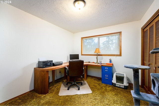 carpeted home office featuring a textured ceiling