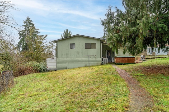 rear view of house featuring central AC unit and a lawn