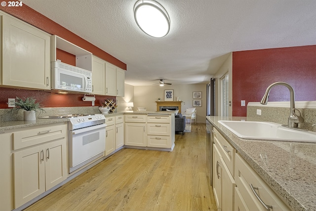 kitchen featuring light wood-type flooring, a textured ceiling, white appliances, ceiling fan, and sink