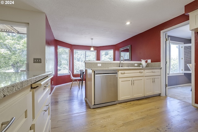 kitchen with hanging light fixtures, white cabinets, stainless steel dishwasher, and light hardwood / wood-style floors