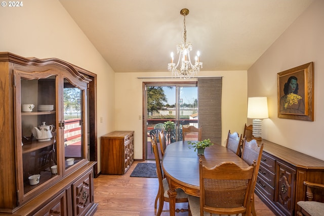 dining area with a wealth of natural light, vaulted ceiling, an inviting chandelier, and light hardwood / wood-style floors