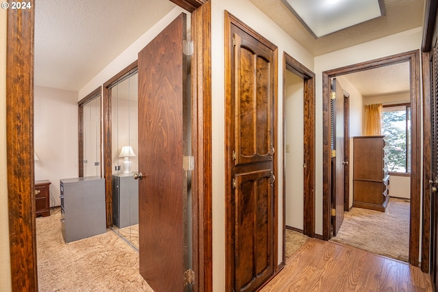 corridor featuring light wood-type flooring and a textured ceiling