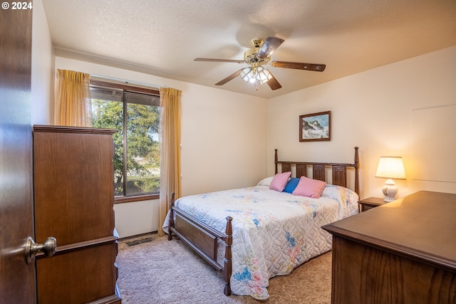 bedroom with a textured ceiling, carpet flooring, and ceiling fan