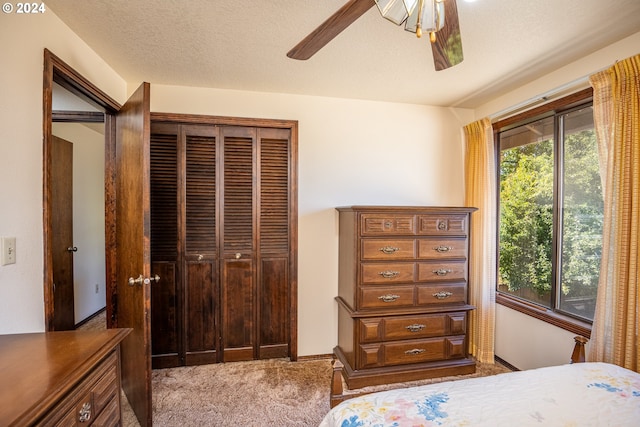 carpeted bedroom featuring multiple windows, ceiling fan, a closet, and a textured ceiling