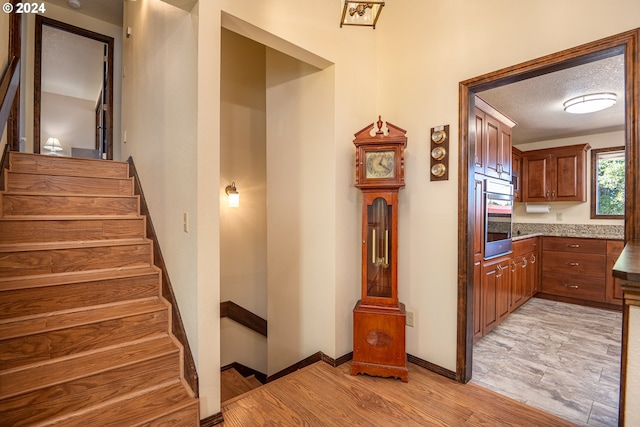 stairs with a textured ceiling and hardwood / wood-style floors