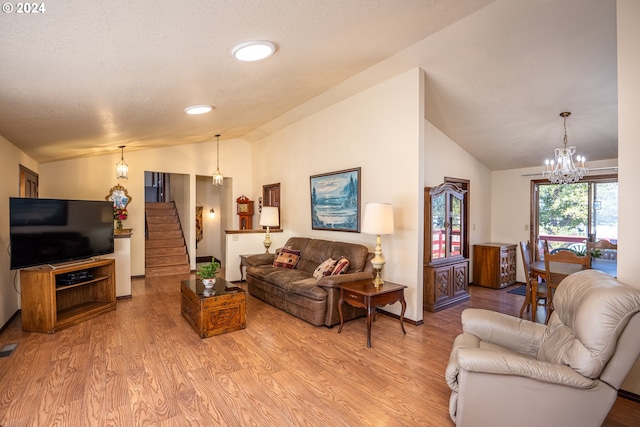 living room featuring light wood-type flooring, vaulted ceiling, a textured ceiling, and a chandelier