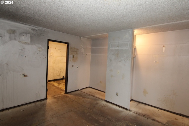 empty room with a textured ceiling and concrete floors