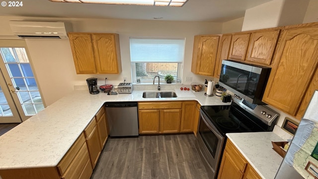 kitchen featuring sink, dark hardwood / wood-style floors, kitchen peninsula, a wall mounted AC, and appliances with stainless steel finishes