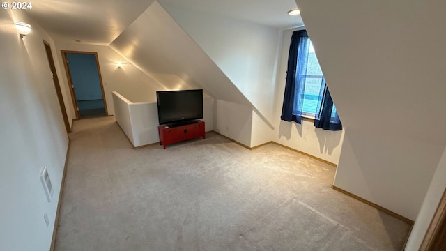 additional living space featuring light colored carpet and vaulted ceiling