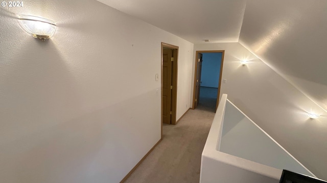 corridor with lofted ceiling and light carpet