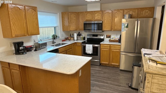 kitchen with dark hardwood / wood-style flooring, kitchen peninsula, sink, and appliances with stainless steel finishes