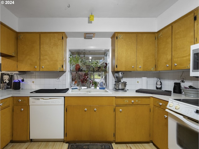 kitchen with sink, white appliances, light hardwood / wood-style flooring, and backsplash